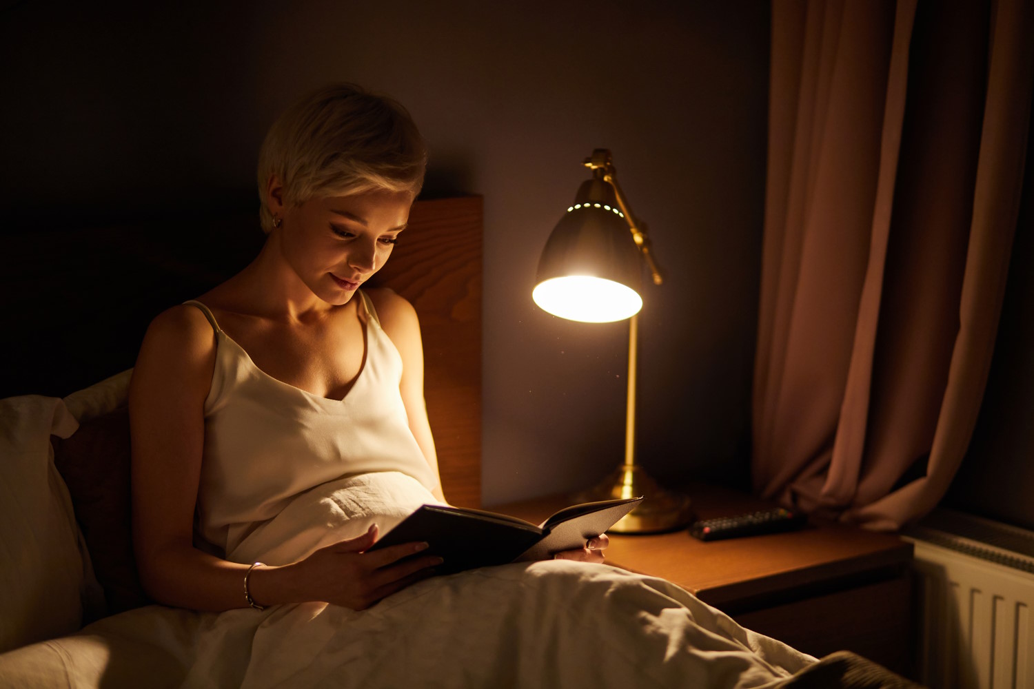 Mujer leyendo con una lámpara al lado